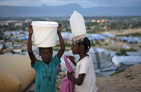 ילדות מובילות מים במחנה פליטים בהאיטי, צילום: איי פי