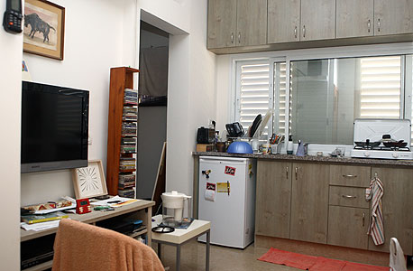 דירה מפוצלת בתל אביב. שולחן העבודה במטבח, מוני החשמל והמים במסדרון