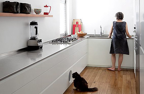 בית בעיצוב אדריכלית טולה עמיר. המטבח מפושט למרכיבים בסיסיים, ארגז החול של החתול מוצנע בצורה אלגנטית