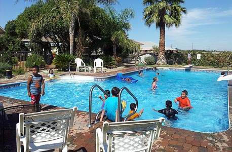 ילדים ממשפחות מצוקה בסטוקטון משתכשכים בבריכה בביתם של ביל וסינדי 