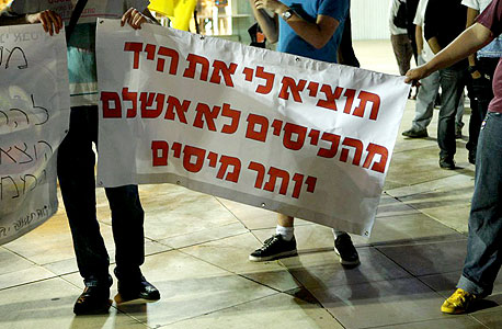 מניפים שלטים בהפגנה בכיכר בימה נגד הגזירות והמסים