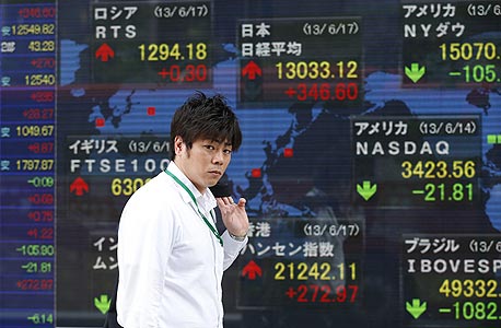 סוחר על רקע מסכים המראים את הירידות בשוק היפני בסוף השבוע שעבר. "אתה מתחיל לראות סדקים בביטחון המשקיעים"