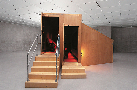 "מכון גן העדן". בעבודה שייצגה את קנדה בביאנלה בוונציה ב-2001. ביתן עץ קטן שבתמונה יוצר אשליה של אולם ענק כמחווה לקולנוענים של פעם