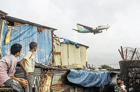 מטוס נוחת בנמל התעופה של מומבאי, ליד אנאוואדי. רק לשישה מאלפי התושבים יש , צילום: בלומברג