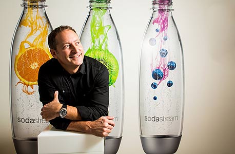 דניאל בירנבאום על רקע קולקציית בקבוקים מעוצבים של סודהסטרים. ימים טובים יותר, צילום: תומי הרפז