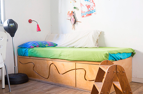 מיטת עץ בחדר הילדים. ליזר עיצב את הגל שמשמש לפתיחת המגירות