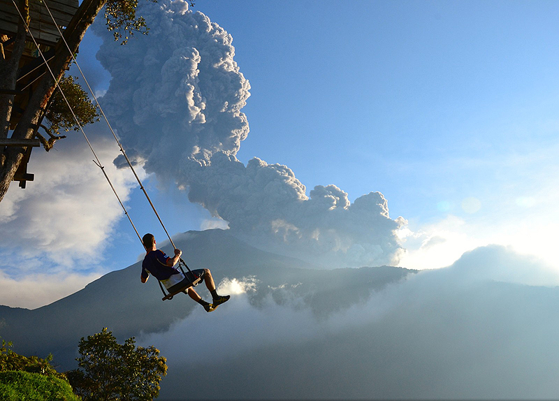 צעיר מתנדנד על נדנדת "סוף העולם" בבאנוס, אקוודור, על רקע הר הגעש הפעיל טונגוראווה. ההתפרצות אירעה בחודש פברואר האחרון. דקות לאחר שצולם, נאלץ הצעיר להתפנות מהאזור בשל ענן האפר שנוצר