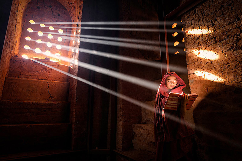 בורמה: נזיר צעיר מוצא נקודת אור מושלמת כדי לקרוא את הספר שלו בתוך בית התפילה שלו