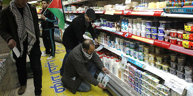 פעילים תולים עלונים הקוראים לחרם מוצרים מישראל במכולת בבית לחם, צילום: איי אף פי