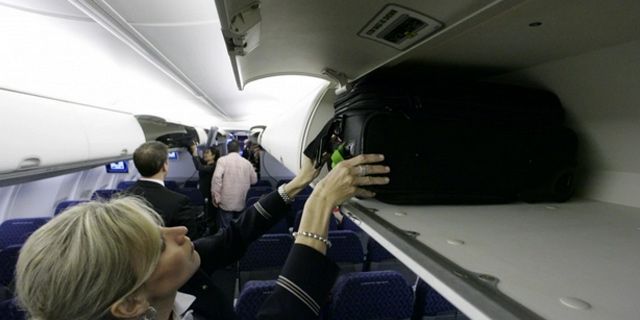 דיילת סוגרת את תאי האחסון במטוס. המטרה היא לאפשר ל-120 נוסעים להעלות  תיק לטיסה, צילום: איי פי