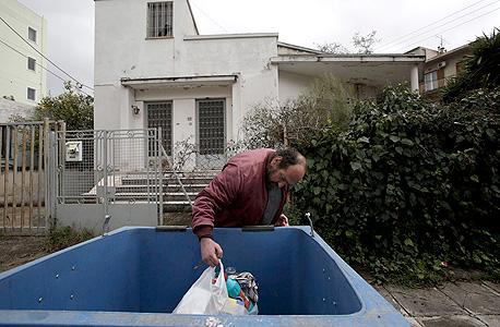 מובטל יווני באתונה מחטט בפח זבל