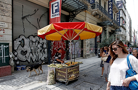 דוכן ריק ומאחוריו חנויות סגורות ביוון, צילום: בלומברג