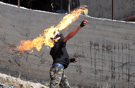 פלסטיני זורק בקבוק תבערה על כוחות ישראלים בבית עומר ליד חברון, צילום: איי אף פי