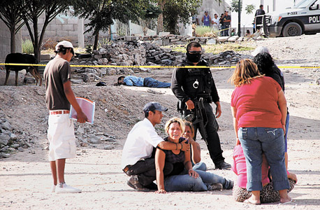 נשים בוכות על רקע גופות ארבעה גברים שנרצחו בידי חברי כנופייה בחוארז, מקסיקו. "המידע שלנו סייע להרחיק אנשים כאלה מהרחובות" , צילום: אי פי איי