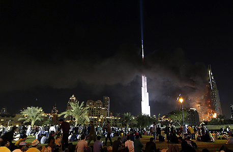 קהל רב ממתין למופע הזיקוקים בחצות, כשהאש מכלה את מלון אדרס הסמוך