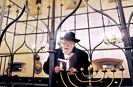 סידון מדליק נרות חנוכה בבית הכנסת העתיק אלטנוישול. פרש מתפקידו כדי להתמסר לכתיבה, ומ"סיבות אישיות" שצופנות שערורייה קטנה