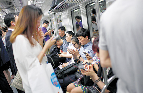 משתמשי סמארטפון ברכבת בסיאול. "המשתמשים מדברים כמו מכורים, כמו אנשים שעברו התעללות", צילום: בלומברג