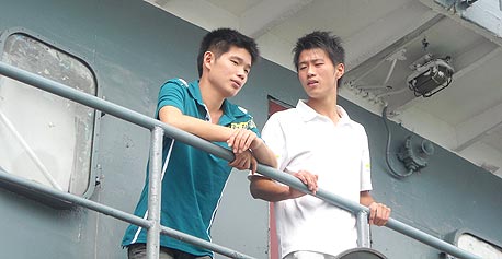 לין ג'יה (משמאל) עם חבר על המעבורת לפינגטאן. "עכשיו נוסעים הרבה צעירים, בגלל המשבר"