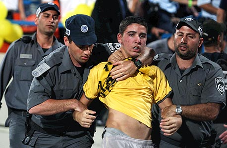 שוטרים עם אוהד כדורגל. ישראל היא המקום היחיד שבו המועדונים אחראים בלעדית על הוצאות השיטור