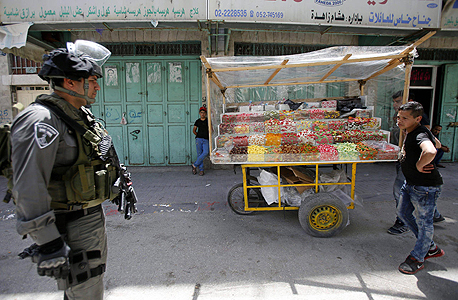 חייל מג"ב לצד סוחר ממתקים פלסטיני בחברון, צילום: אי פי איי
