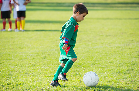 ילד משחק כדורגל. יש לכך מנבאים פיזיולוגיים, חברתיים ופסיכולוגיים