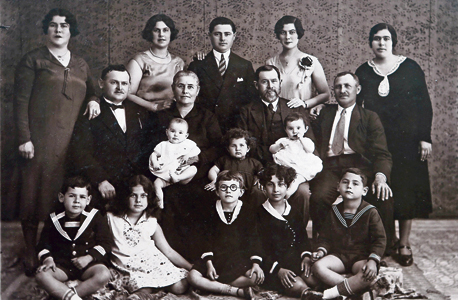 1930, לילי אלשטיין (התינוקת במרכז מימין) ואחותה התאומה עדנה (במרכז משמאל) בנות פחות משנה, האח נעם (יושב מימין) בן ה־8 וההורים שולמית ומשה (הזוג העומד בצד שמאל) בונשטיין עם סבים, דודים ובני דודים בזכרון יעקב, צילום רפרודוקציה: אלעד גרשגורן