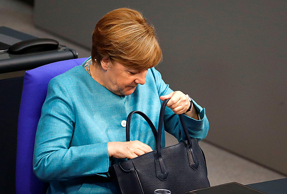 אנגלה מרקל קנצלרית גרמניה מסתכלת בתיק, צילום: רויטרס