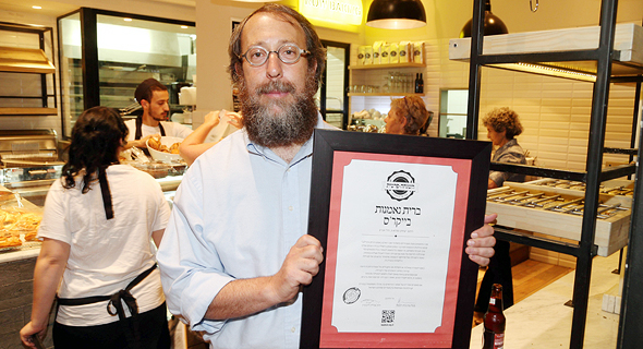 הרב אהרון ליבוביץ עם תעודת כשרות של "השגחה פרטית" בקפה בייקרס בתל אביב