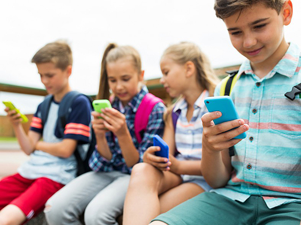 Schoolkids using smartphones (illustration). Photo: Shutterstock