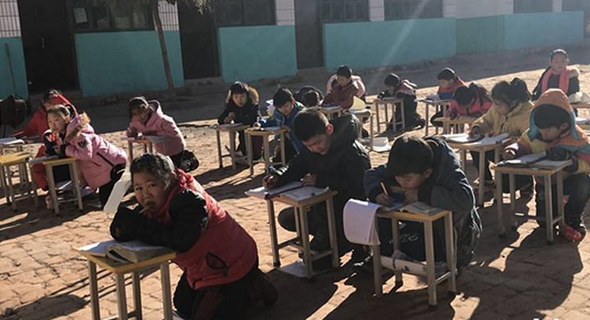 תלמידים בסין לומדים בחצר כדי להתחמם בשמש