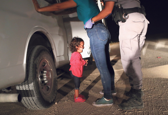 פעוטה בת שנתיים מהונדורס בוכה בעת ששוטר גבול עוצר את אמה גבול ארה"ב מקסיקו. לא מבדילים בין מבקשי מקלט לחברי כנופיות