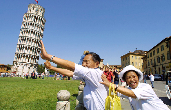 מוסף שבועי 28.6.18 דרקון עם דרכון תיירים סינים על רקע מגדל פיזה איטליה, צילומים: גטי אימג'ס