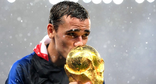 אנטואן גריזמן, חלוץ נבחרת צרפת, מנשק את הגביע העולמי. "כולם בכו - הוא עזב את הבית בגיל צעיר"