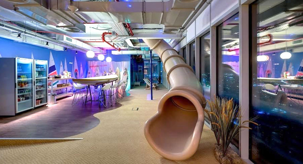 A slide leading to a furnished dining area at Google