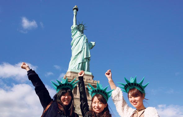 Chinese tourists pose in front of the Statue of Liberty. Photo: Reuters