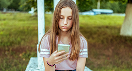 A child looking at her smartphone. Photo: Shutterstock