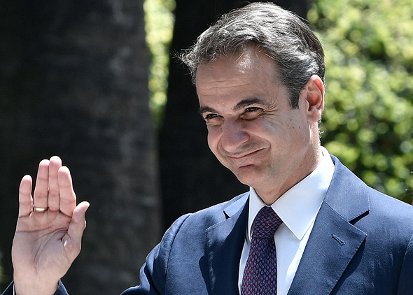 ראש ממשלת יוון קיריאקוס מנופף לשלום באצבעות סגורות. הקפידו לנהוג כמותו