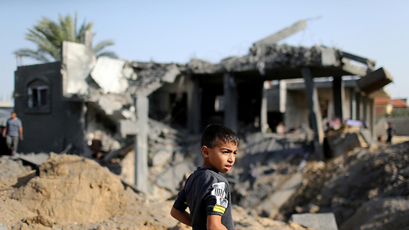 ילד וברקע מבנים שהותקפו ברצועת עזה , צילום: רויטרס
