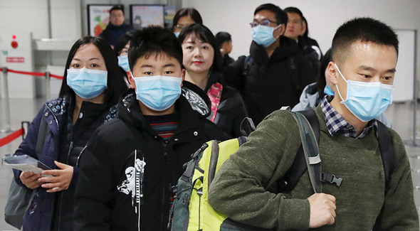נוסעים מגיעים ליפן מסין בינואר, עם מסיכות למניעת הידבקות. 