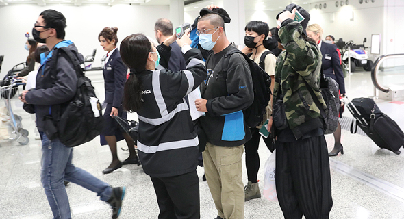 נוסיעם בשדה התעופה בהונג קונג עם מסיכות נגד הדבקות מווירוס הקורונה