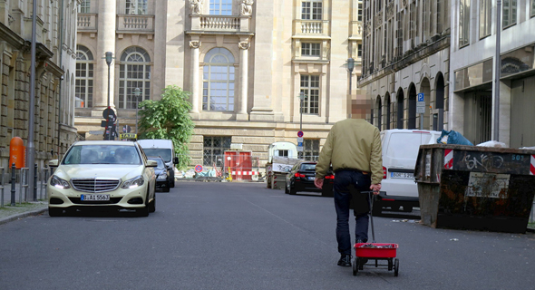 כך זה בוצע: האמן סיימון ווקרט עם העגלה ועליה הסלולרים בברלין