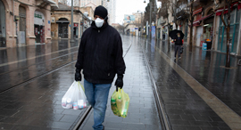 A man walking with groceries in an empty street in Jerusalem. Photo: Amit Shabi