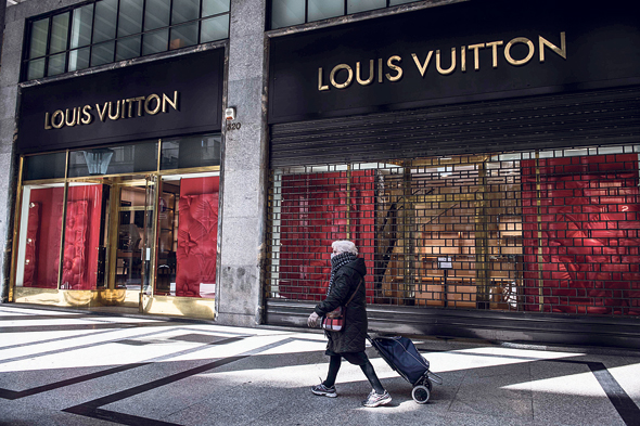 אשה חולפת על פני חנות סגורה של ויטון בטורינו, איטליה. LVMH תרכוש 40 מיליון מסכות מסין עבור בתי חולים בצרפת