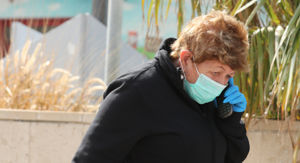 A woman walking and wearing a mask and gloves in Israel. Photo: Photo: Gadi Kabalo