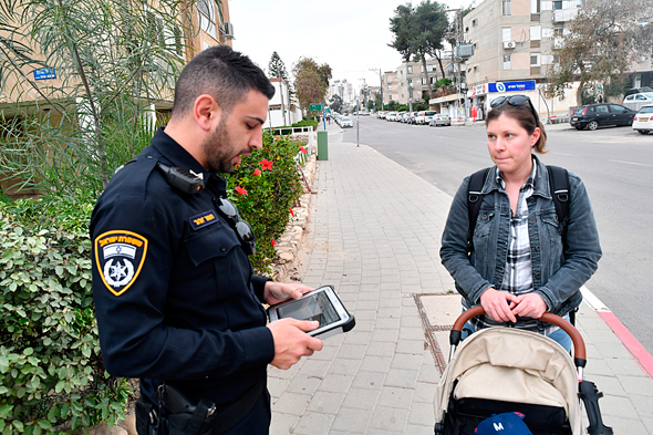 שוטר מתשאל אשה לגבי המרחק מביתה בזמן משבר הקורונה