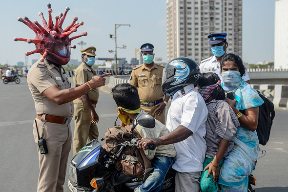 שוטר הודי עם קסדה בצורת קורונה מזהיר אזרחים לא להיכנס לאזור בידור, צילום: איי אף פי