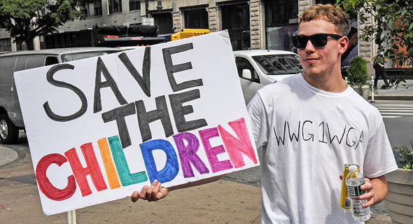 מפגין נושא שלט Save The Children, צילום: רויטרס