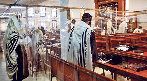 Jewish worshipers praying in an Israeli synagogue separated by nylon Covid-19 barriers during the High Holidays. Photo: AFP