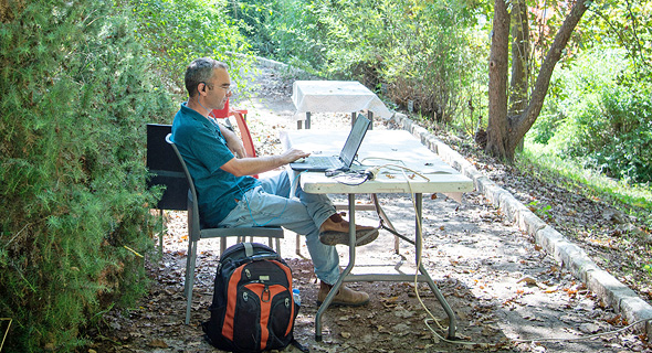 A man works outside on his computer at the Jerusalem Botanical Gardens. Photo: Yoav Dudkevitch