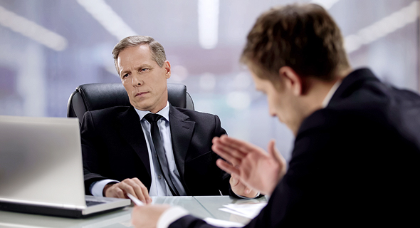 A manager looking at figures while ignoring his employee. Photo: Shutterstock